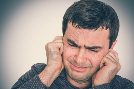 耳鸣声素材男人捂住耳朵以防止噪音过度声背景