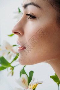 长着白色百合花在背景中装扮的年轻美皮肤女青图片