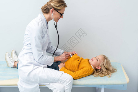 年轻女医生用听诊器倾听小女图片