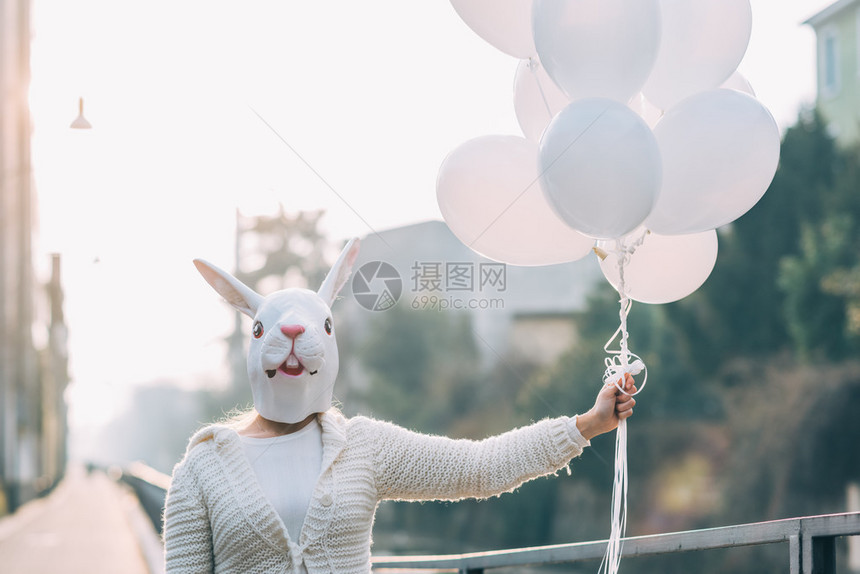 半身戴面具的年轻千禧女拿着白色气球图片