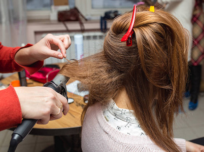 美发师用电熨斗卷发钳卷发女人的头发制作女人图片