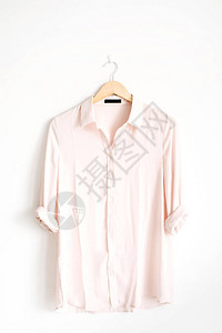 白色背景附近衣架上美丽时尚粉色女式衬衫的前视图片