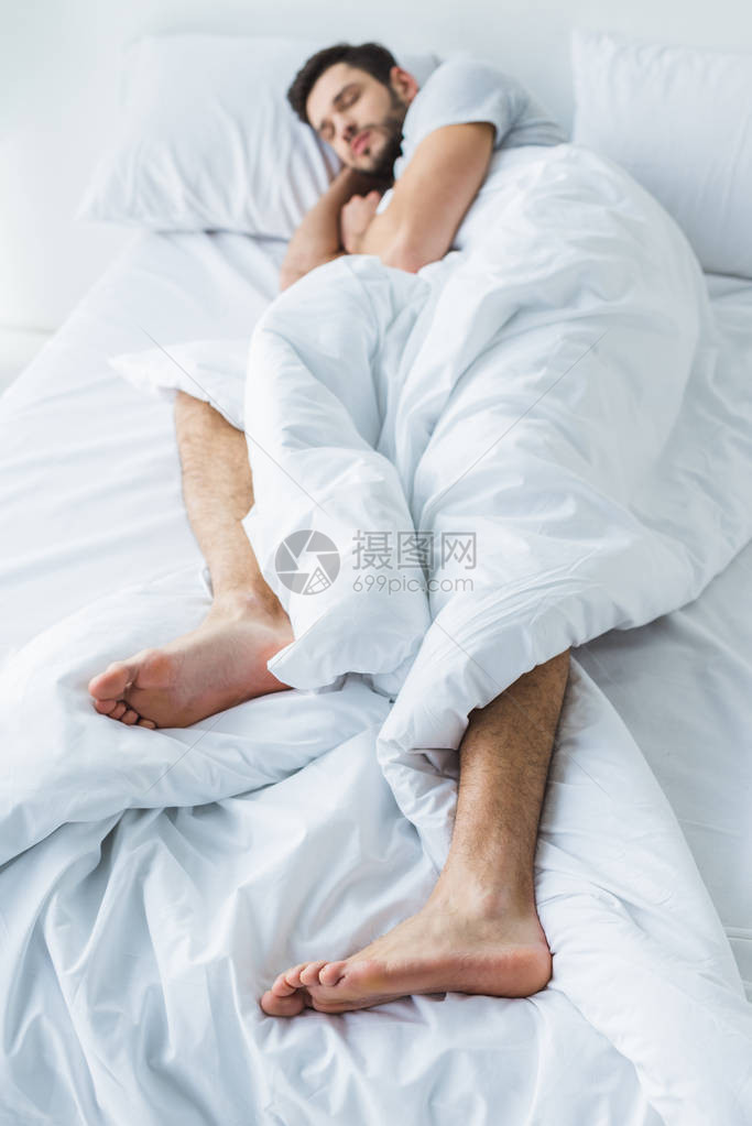 男子在白床上睡觉图片