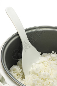 用白色背景上的塑料勺子在炊具锅里煮熟的米饭图片