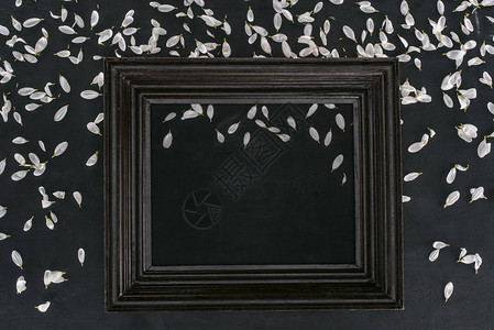 黑色背景上带有花瓣的老式木制框架的顶视图背景图片