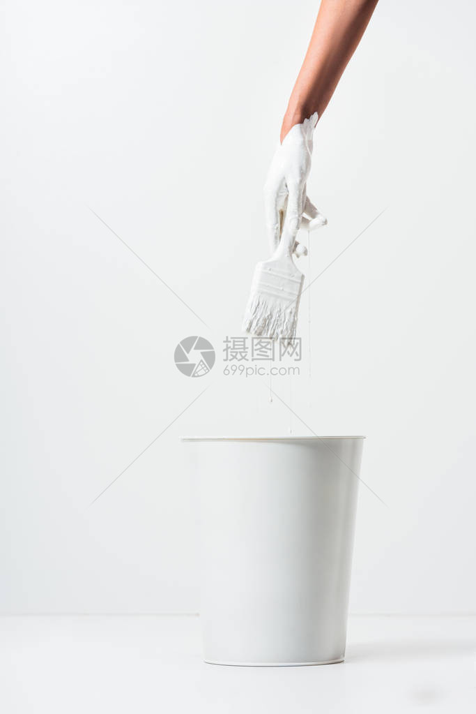 妇女用白油漆在白桶上方一桶子上方的白图片