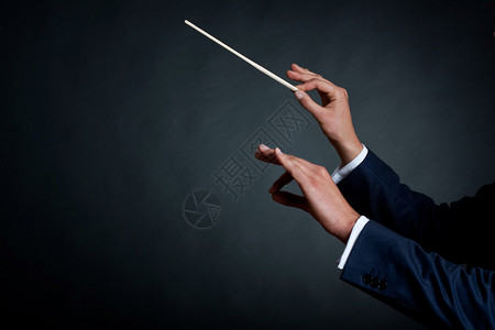 男管弦乐团指挥员以他的指挥棒在音乐会图片