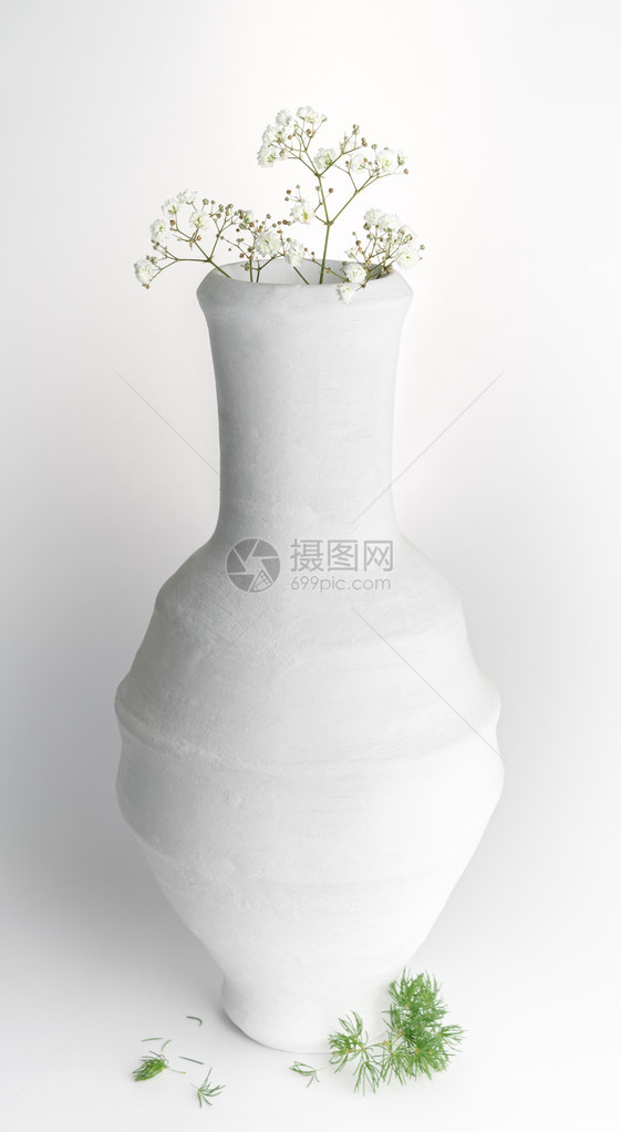 白色陶瓷花瓶和白色背景上小白花的静图片