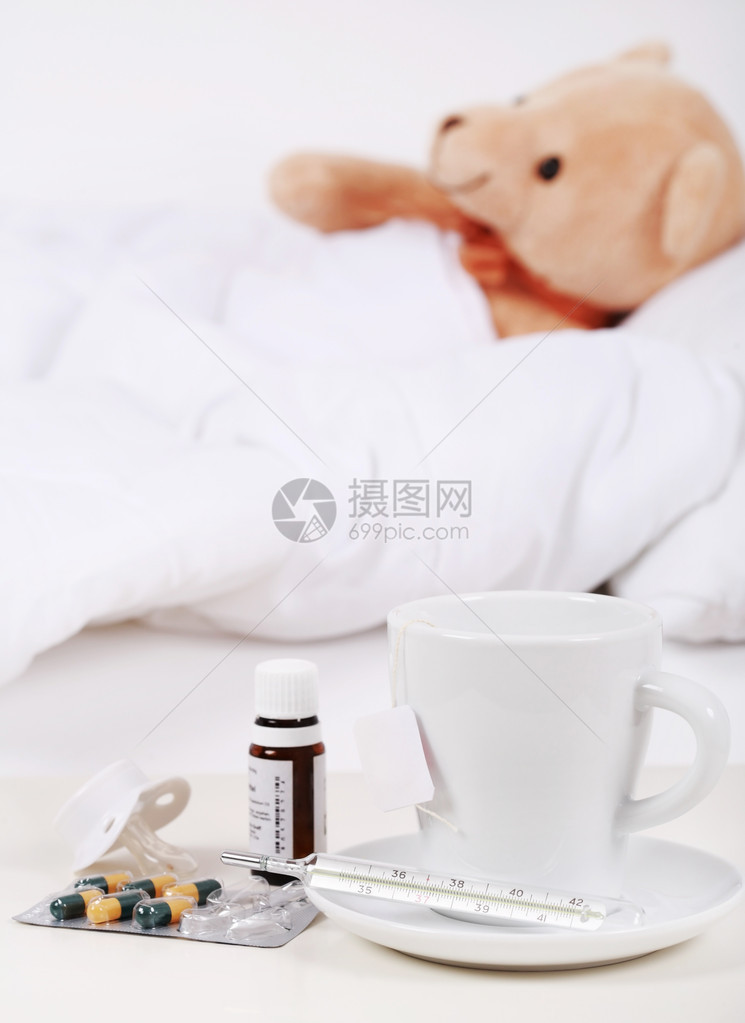 泰迪熊躺在床上喝杯茶和药图片