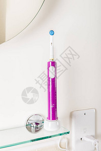 浅色背景浴室架上的电动可充电牙刷图片