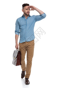 穿着蓝色衬衫的随身男子带着公文包走着行走图片