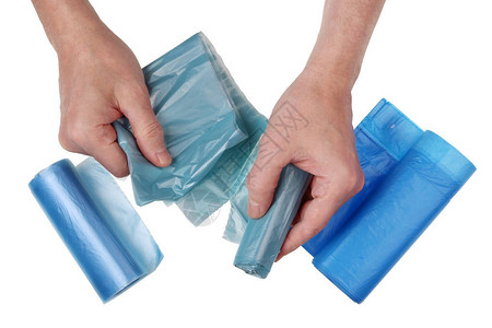 一位老人从一整卷中撕下一个蓝色塑料垃圾袋孤立的顶视图工图片