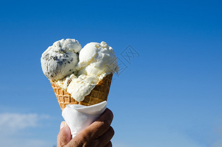 手拿着在蓝天的一个冰淇淋锥体图片