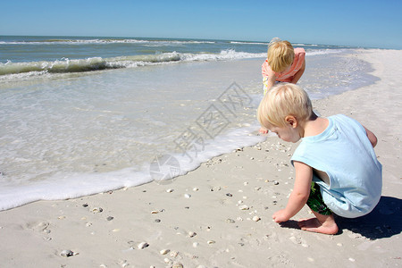 两个小孩一个男孩和他的小弟在海边的背景图片