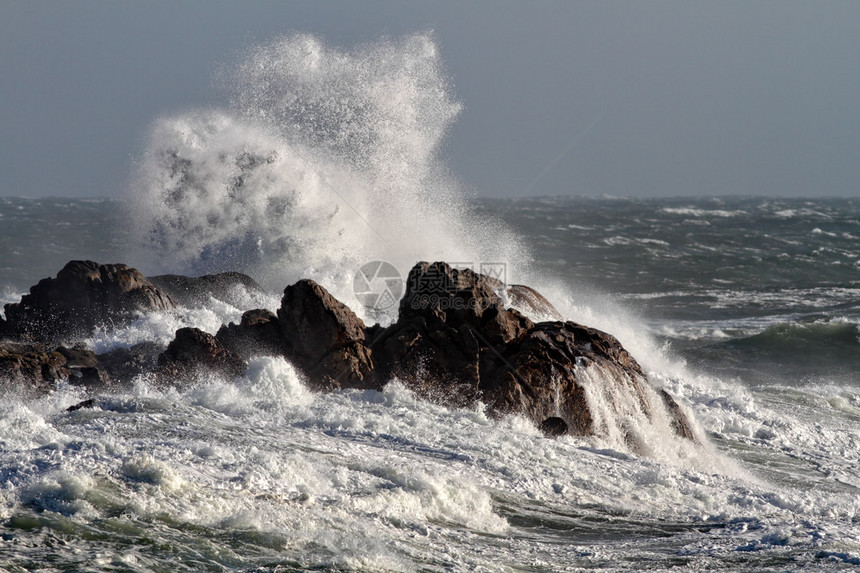 在一个刮风的下午巨浪拍打着岩石图片