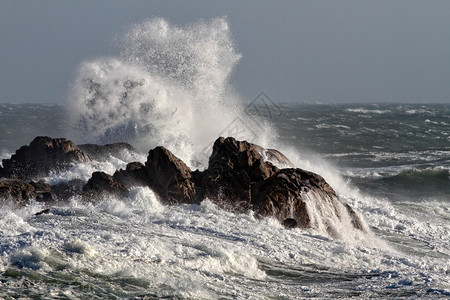 在一个刮风的下午巨浪拍打着岩石图片
