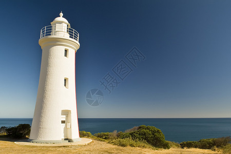 宏伟的白色水洗灯塔俯瞰着深蓝色的海洋背景图片