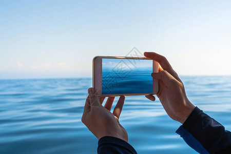 使用智能手机拍摄蓝海和天空旅游和旅行概念照片的图片