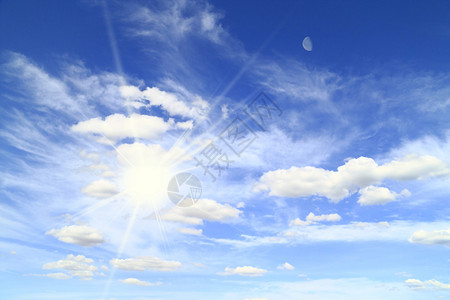 蓝天上的太阳和月亮与白色的羽毛状云彩图片