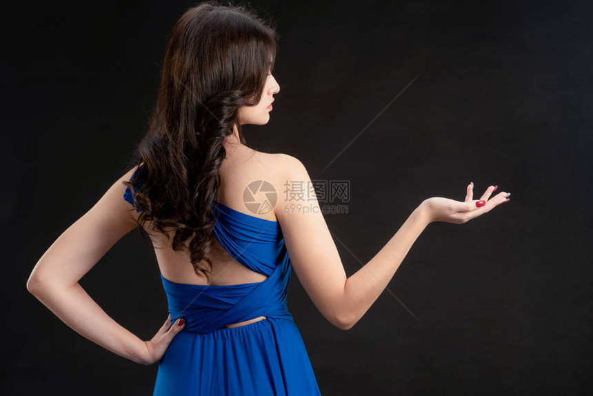 穿着蓝裙子的美女时装模特站在黑暗背景图片
