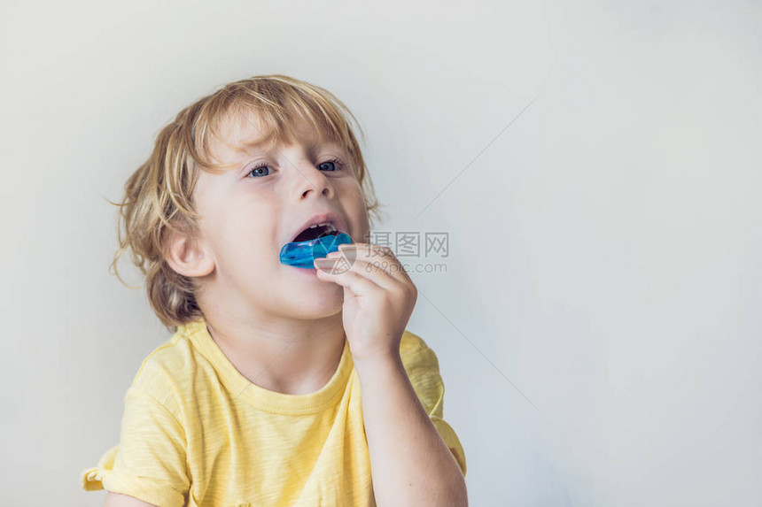 三岁男孩展示肌功能训练器以阐明口呼吸习惯有助于平衡正在生长的牙齿并纠正咬合矫图片