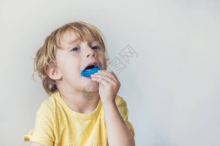 三岁男孩展示肌功能训练器以阐明口呼吸习惯有助于平衡正在生长的牙齿并纠正咬合矫背景图片