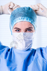 身穿蓝色保护制服帽子和面具的女外科图片
