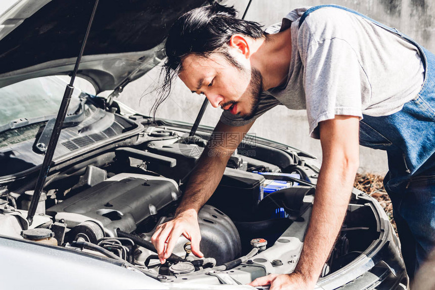 专业汽车机械师在汽车服务中统一固定汽车发动机和修理汽车引图片
