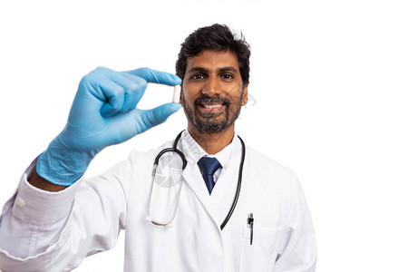 友好的印度男医生持有白色胶囊手指与图片