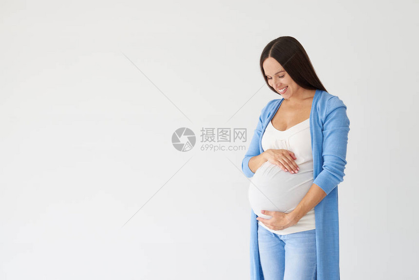 亲切的孕妇在工作室中拥图片