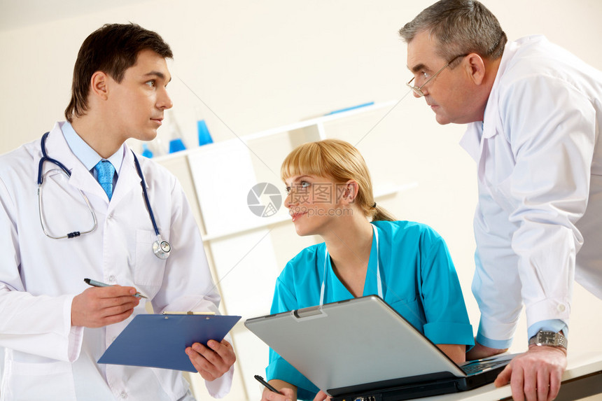 三名临床医生在医院进行严肃对话的照片图片
