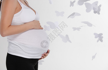 在白色背景的孕妇腹部与蝴蝶图片