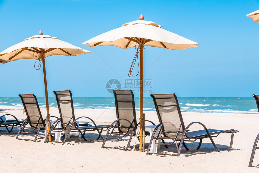 蓝色天空热带海滩上的沙滩椅和遮阳伞图片