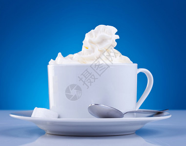 咖啡和蓝底的奶油咖啡杯上面有奶油图片