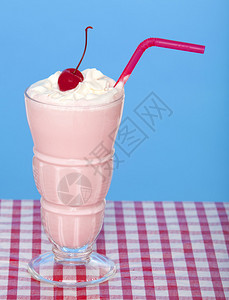 蓝色背景野餐桌布上的草莓奶昔图片