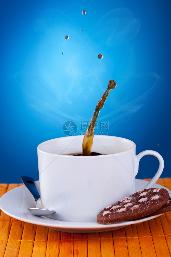 在蓝背景的咖啡杯中泡在一杯咖啡里图片