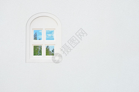 白色混凝土墙上的白色窗口外面的玻璃窗外有松树林和阴图片