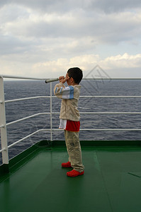 一艘游轮甲板上的儿童男孩向地中海港口的船舶看玻璃图片
