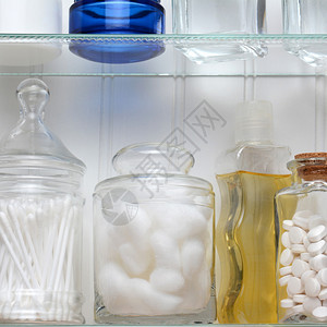 药柜的两个架子的特写镜头一瓶药片棉球棉签各种罐子和几瓶肥皂和乳图片