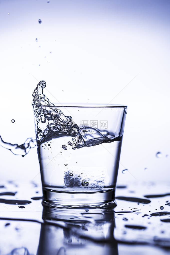 一杯泼水与冰块和水滴图片