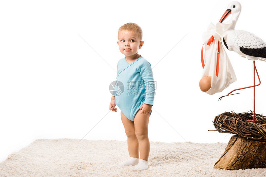 穿着蓝体装的可爱小孩男站在地毯上图片