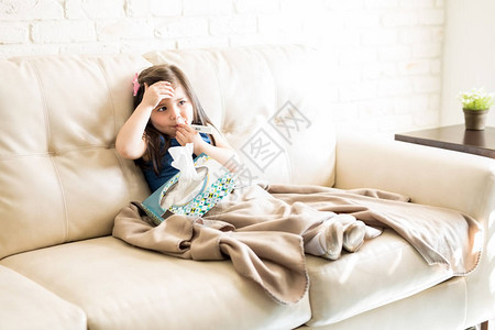 女孩将温度计放在嘴里在客厅内沙发上举图片