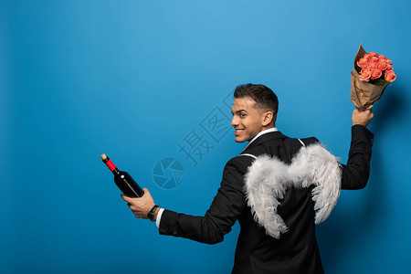 带着白翼的笑商人背影酒瓶和蓝底花背景图片