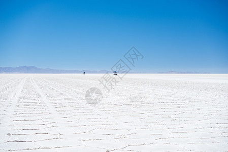 远处有两辆4x4车辆探索世界著名的乌尤尼盐滩图片