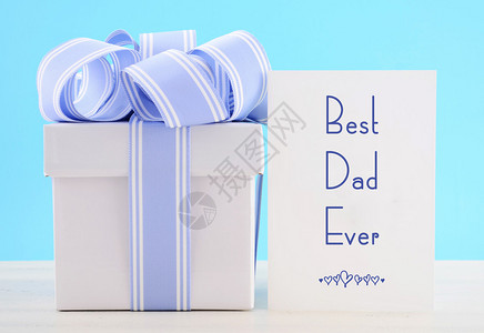 父亲节快乐礼物与蓝色和白色丝带与最好的爸曾经贺卡在白色木桌上和图片