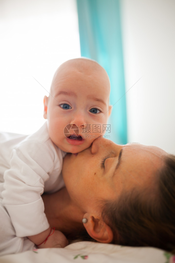 照顾母亲的妈亲吻着她孩子的脸图片