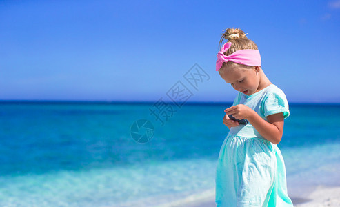 小女孩在海边打电话拍照图片