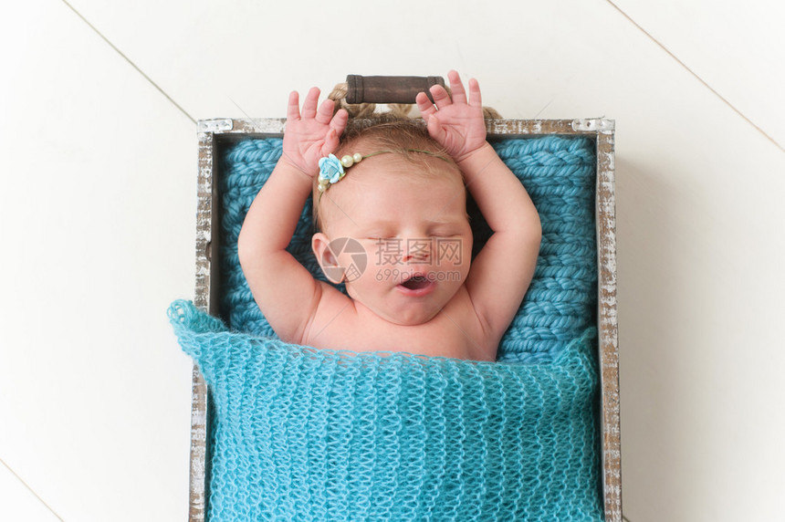 一个张开双臂打呵欠九天大的新生女婴的画像图片