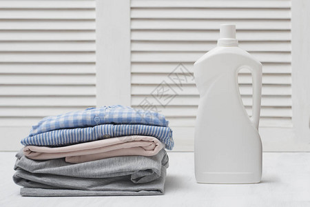 一堆折叠的衣服和洗涤剂瓶白色背景图片