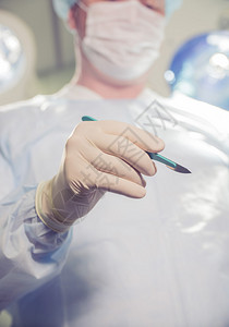 一名医生在手术室背景上拿着手术刀图片